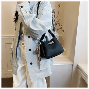 Gros plan de détail d'un sac seau chic en cuir noir texturé avec fermeture à verrou.