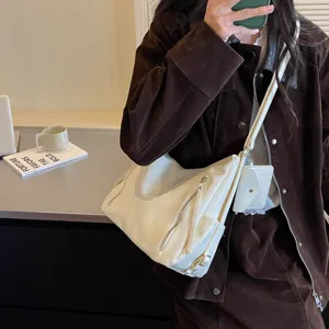 Close-up detail of stylish white leather shoulder bag with side zipper and mini pouch.