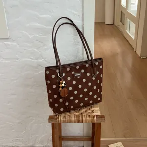 Brown polka dot tote bag detail view, large capacity shoulder bag with chic charm pendant.