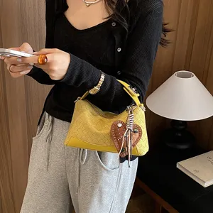 Détail du sac à main vintage tissé jaune sous les bras avec un élégant charm cœur.