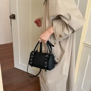 Primo piano dettagliato di una borsa a cilindro nera con fibbie in metallo e manici.
