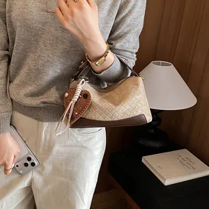 Vue détaillée d'un sac à main tissé rétro avec charm cœur, élégant et compact au quotidien.