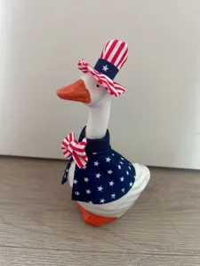Detailed shot of patriotic goose figurine wearing star-spangled top hat and cape set.