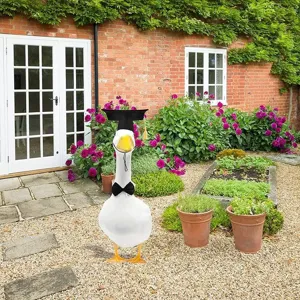Graduation outfit set for large white goose statue, featuring black cap and stylish bow tie.