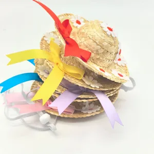 Close-up detail of mini straw pet hats featuring colorful ribbons and daisy flower decorations.
