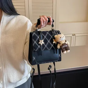 Zaino nero elegante con motivo a losanghe, ciondolo orsetto e stella per uso quotidiano.