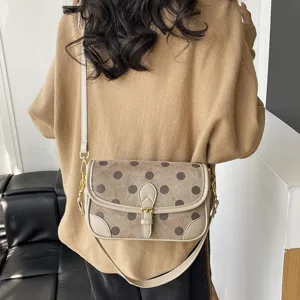 Gedetailleerd overzicht van retro suède schoudertas met polkadots en chique gesp.