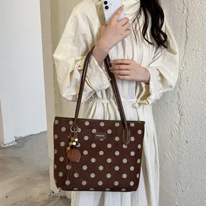 Brown polka dot tote bag detail showing stylish pattern and matching hanging pendant.