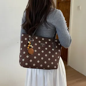Brown polka dot tote bag detail showing soft suede material and cute hanging pendant ornament.