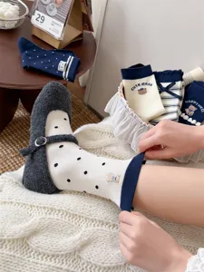 Close-up detail of Japanese cute bear embroidered polka dot mid-tube socks with navy blue roll cuffs.