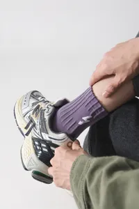 Detailaufnahme von lila gerippten Socken mit weißer Blitzstickerei und Sneakern.