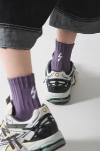 Detaillierte Nahaufnahme von violetten Rippsocken mit weißer Blitzstickerei im Detailbereich.