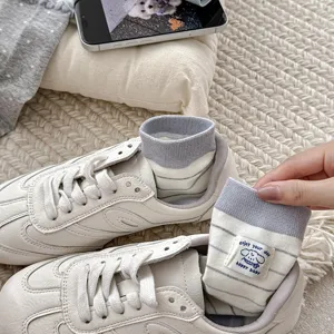 Detail view of grey striped women crew socks featuring cute cartoon bear patch retro Korean style.