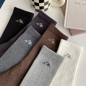 Men's stylish cotton crew socks detail shot featuring minimalist mountain embroidery design.