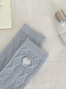Close-up detail of grey knit socks featuring diamond pattern and cute heart embroidery.