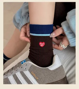 Gros plan détaillé de chaussettes mi-hautes à cœur brodé style coréen et blocs de couleur.