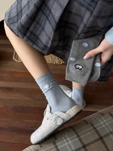 Detail shot of women's mid-calf socks featuring cute heart embroidery and cartoon knit patterns.
