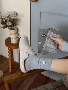 Detailed close-up of grey patterned mid-calf socks and warm plush clogs in cozy room.