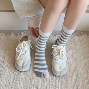 Detailed close-up of striped split-toe two-finger tabi socks paired with fashion shoes.
