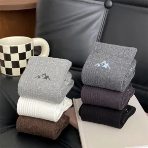 Detailed view of trendy men's cotton crew socks with mountain embroidery in multiple colors.