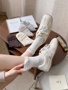 Detailansicht von Damen Baumwolle Socken mit Blumenmuster und stylischen Sneakers.