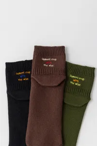 Detail shot of stylish embroidered crew socks featuring unique quote text in three colors.