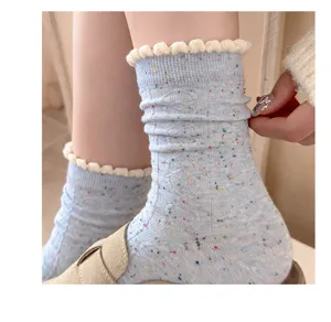 Close-up detail of light blue speckled ruffled mid-calf knit slouch socks for women.