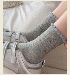 Detailed close-up of grey neppy mid-tube socks with blue ruffled cuffs, cozy knit texture.