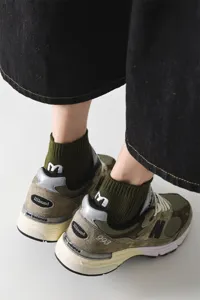 Detailansicht von olivgrünen Herren Baumwollsocken mit cooler Fersenstickerei und stylischen Sneakern.