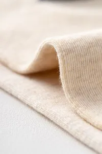 Close-up macro detail of soft beige cotton knitted fabric texture for premium casual socks.