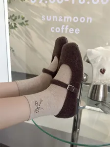 Close-up of cozy brown fuzzy Mary Jane shoes paired with cute bow embroidered mid-calf socks.