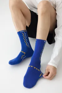 Close-up detail van de blauwe sportsokken met honingraat breipatroon en geweven tekst.