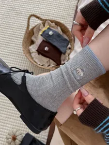 Graue Wadenstrümpfe mit süßem Hündchen-Stick und blauem Bündchen, gemütliches und stylisches Detail.