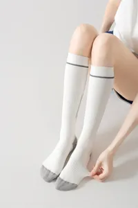 Vista dettagliata di calze sportive bianche da compressione per polpacci donna con righe grighe.