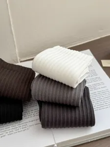 Detailed close-up of folded cotton crew socks in neutral tones with fine ribbed knit texture.