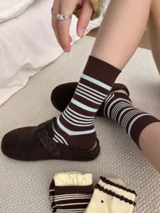 Detailaufnahme von retro gestreiften Damen Baumwollsocken kombiniert mit gemütlichen Hausschuhen.