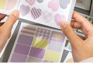 Detalle de cuaderno de pegatinas pastel con corazones y cuadros para decorar agenda.