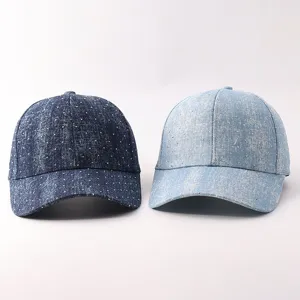 Vista detallada de elegantes gorras de béisbol de mezclilla con pedrería y visera curvada.