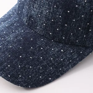 Vista detallada de la gorra de béisbol de mezclilla azul oscuro adornada con pedrería brillante.
