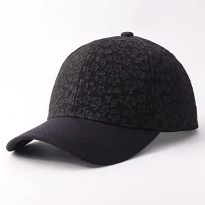 Detail shot of black floral embossed baseball cap, textured flower pattern, curved brim.