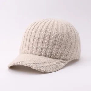 Close-up detail of soft beige knitted baseball hat, showing clear rib texture and curved brim.