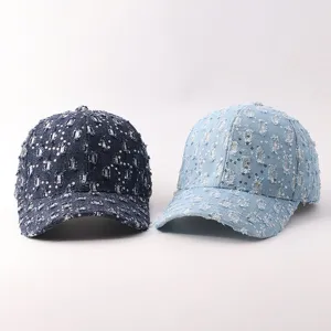 Primer plano de gorras de béisbol de mezclilla desgastada con lentejuelas y visera curva.