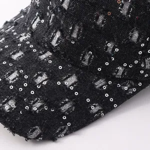 Primer plano detallado de gorra de béisbol de mezclilla negra con roturas, lentejuelas y estrás.