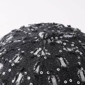 Vista detallada de la gorra vaquera negra desgastada con lentejuelas y textura única.