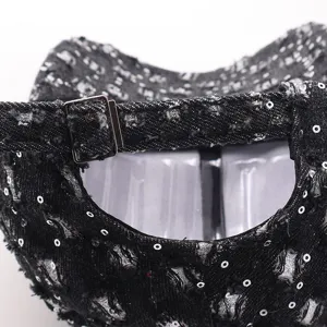 Primer plano de la hebilla metálica ajustable en la gorra de béisbol negra con lentejuelas.