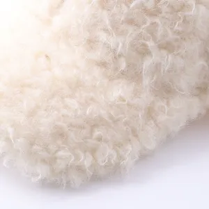Primer plano detallado del material de vellón rizado blanco crema con textura suave y esponjosa.
