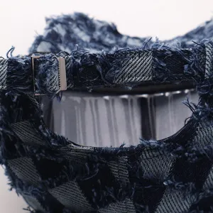 Primer plano detallado de la hebilla metálica ajustable y textura de mezclilla deshilachada.