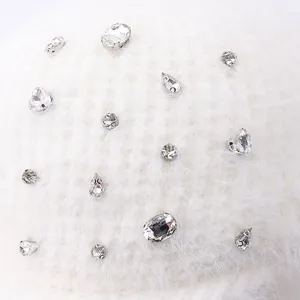 Gros plan sur les détails d'un bonnet d'hiver en tricot blanc orné de strass étincelants.