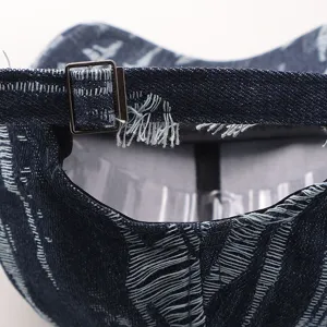 Primer plano de la correa trasera y hebilla metálica de la gorra vaquera desgastada.