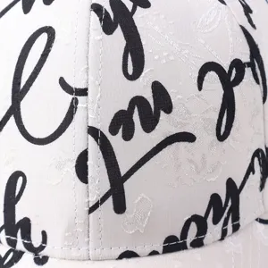 Detailed view of a stylish white baseball cap featuring black graffiti letter prints.